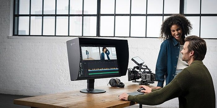 Zwei Filmschaffende arbeiten an einem Monitor mit einer Filmschnitt-Timeline
