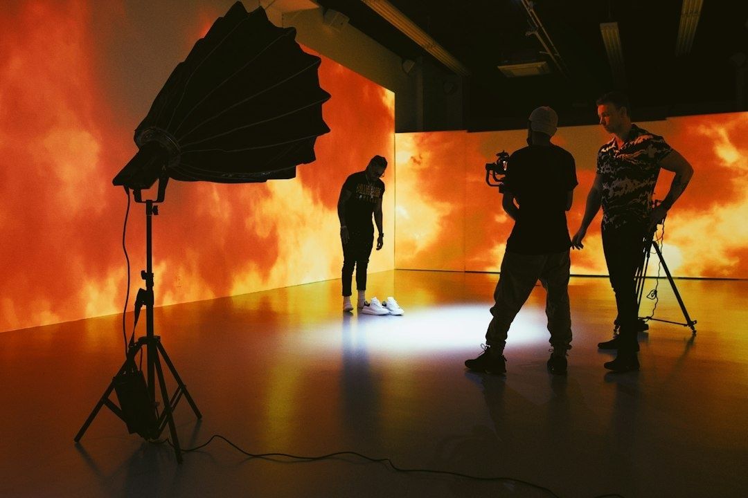 Filmset mit Kamerateam vor leuchtend orangefarbenen Bildschirmen